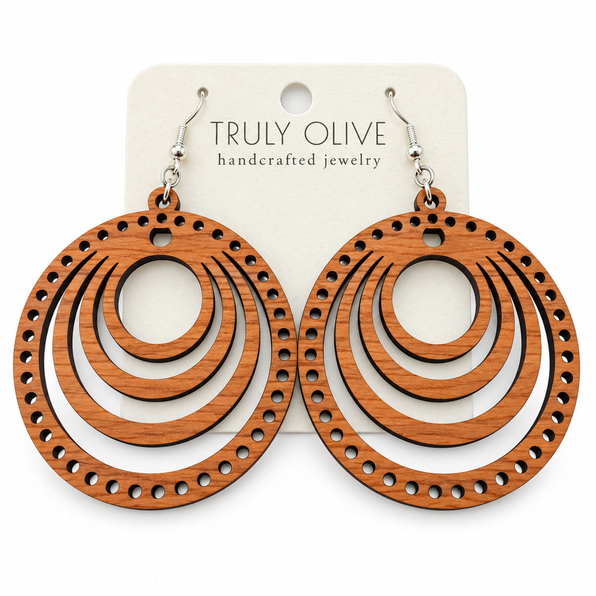 Pair of warm Cherry round wood earrings with concentric cutouts and a dotted edge on a Truly Olive card against white.