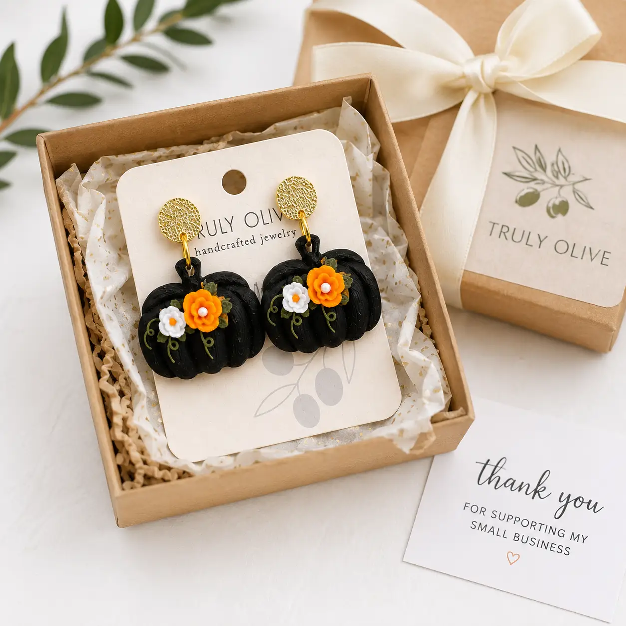 Festive social media product image in truly olive packaging featuring black pumpkin floral statement earrings with elegant fall and Halloween styling. This is how Truly Olive packages up their products.