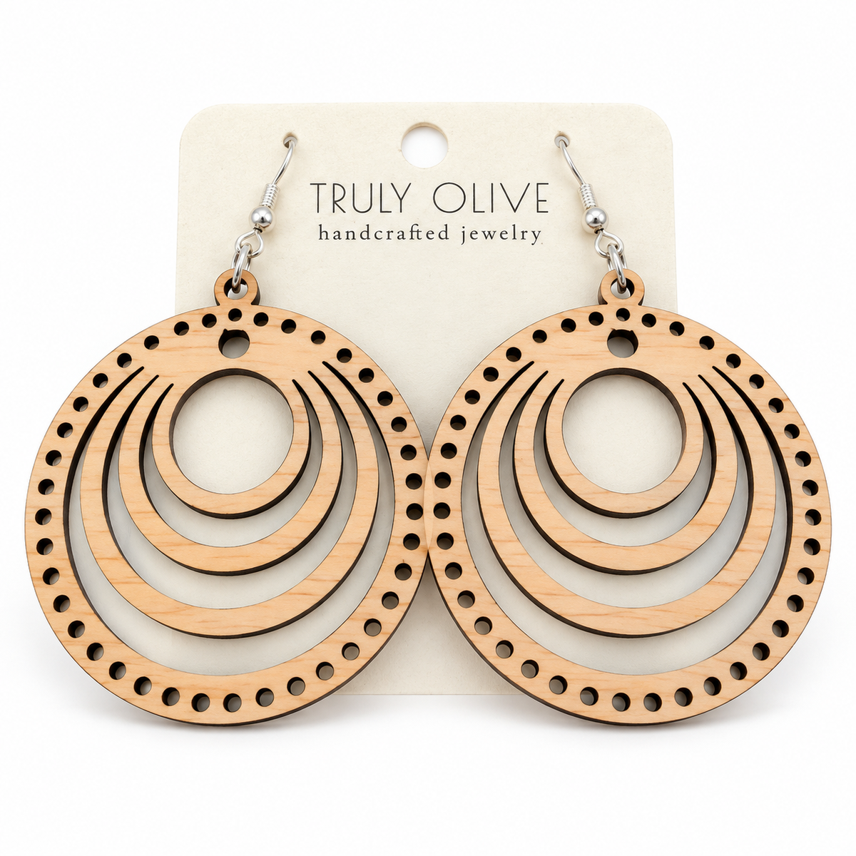 Pair of pale Maple round wood earrings with concentric cutouts and a dotted edge on a Truly Olive card against white.