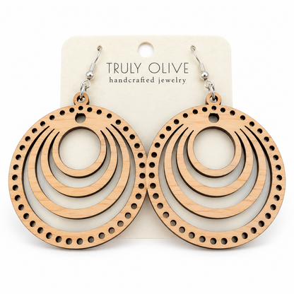 Pair of pale Maple round wood earrings with concentric cutouts and a dotted edge on a Truly Olive card against white.