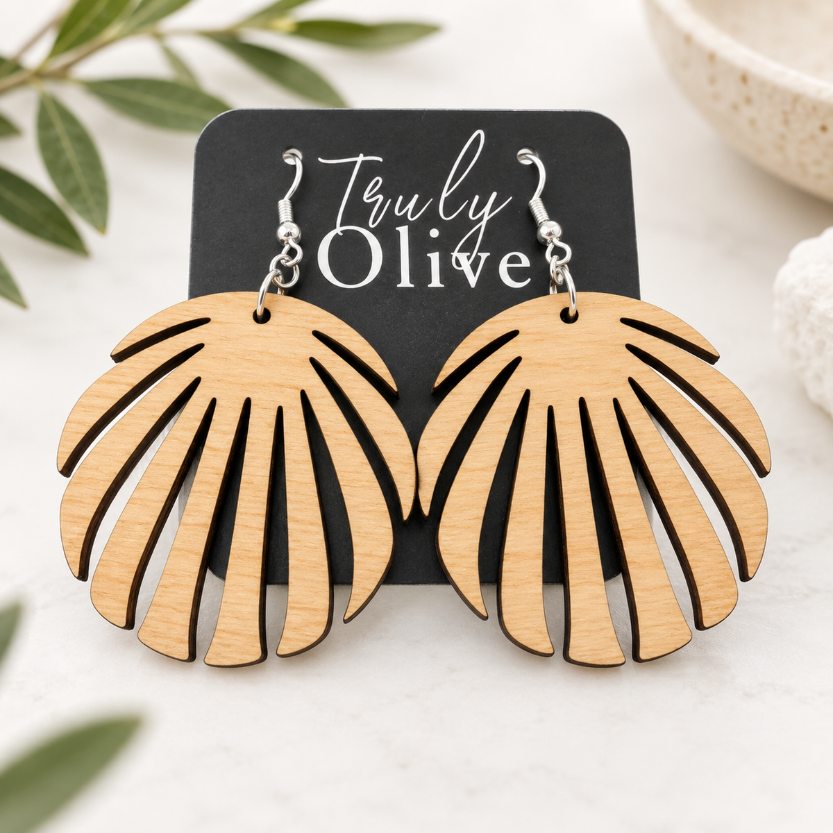Close-up of the Maple wood grain, dark cut edges, and silver-tone hooks on one leaf earring.