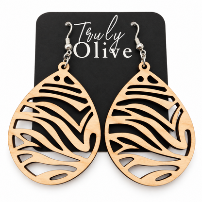 Pale Maple wood teardrop earrings with zebra-inspired cutouts and silver-tone hooks on a black Truly Olive card against white.