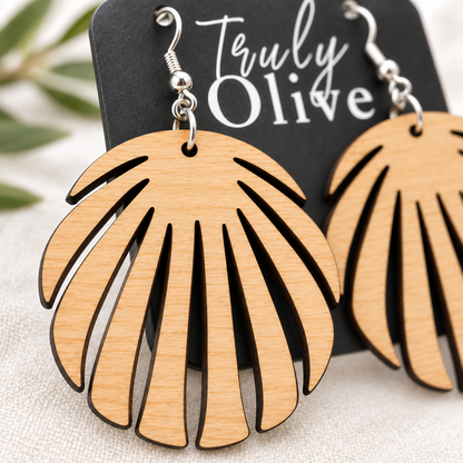 Overhead view of Maple wood leaf earrings on a Truly Olive card over cream linen. A blurred olive branch.