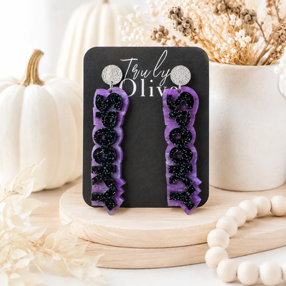 Orange and purple SPOOKY Halloween statement earrings displayed on Truly Olive earring cards with festive pumpkins and boutique fall décor.