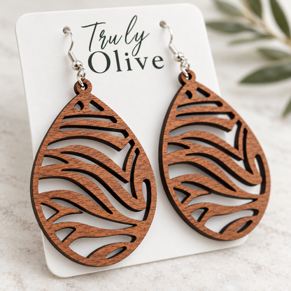 Close-up of Sapele wood earrings showing the grain, dark cut edges, zebra-inspired openings, and silver-tone hardware.