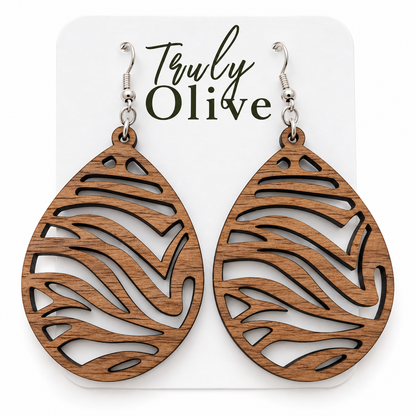 Walnut wood teardrop earrings with darker grain and sweeping zebra cutouts on a white Truly Olive card.