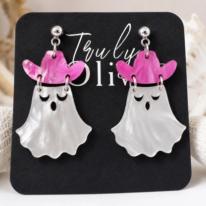 Handcrafted cowgirl ghost Halloween earrings featuring a pearly white ghost with a dark pink cowboy hat, displayed on a black Truly Olive jewelry card against a clean white background.