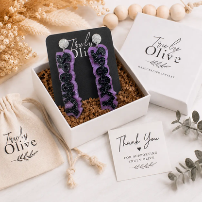 Purple SPOOKY earrings packaged with Truly Olive branding, gift box, pouch, and boutique-ready presentation.