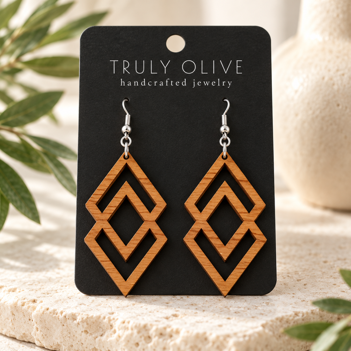 Connected Diamond wood earrings in Cherry stain on a black Truly Olive card in a softly lit styled setting.