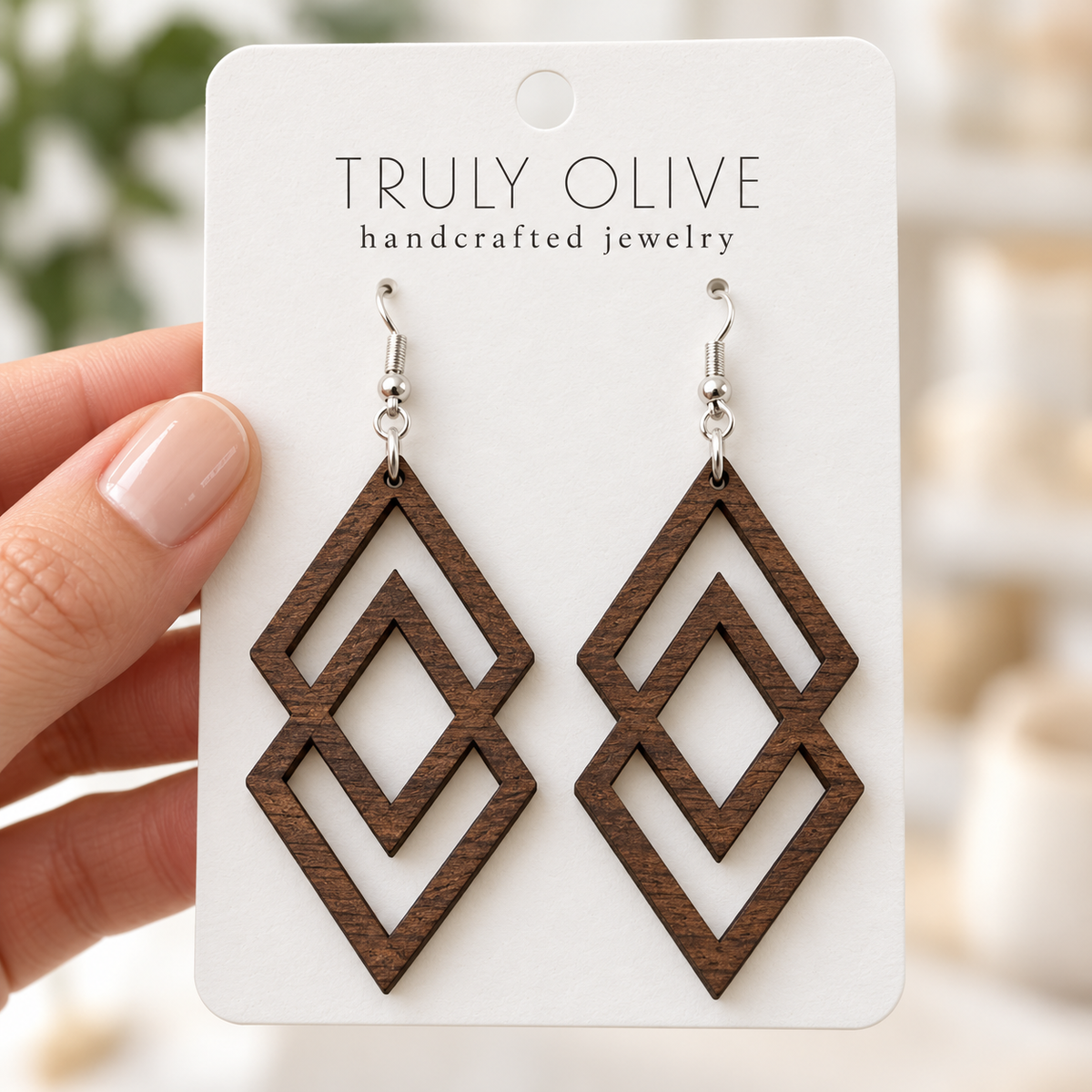 Hand holding a white Truly Olive card with Walnut Connected Diamond wood earrings.