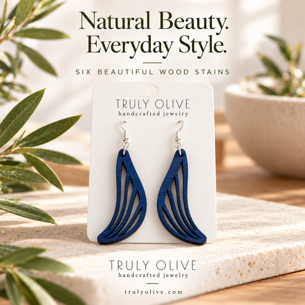 Marine Blue Swept Wing wood earrings in a styled product image with Truly Olive branding.