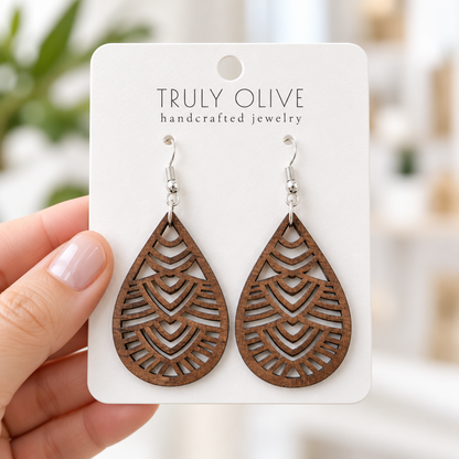 Hand holding a white Truly Olive card with Walnut Geometric Teardrop wood earrings.