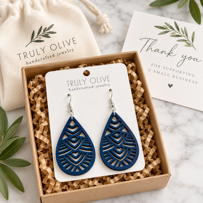 Marine Blue Geometric Teardrop wood earrings on a white Truly Olive card in a kraft box beside a branded pouch and thank-you note.