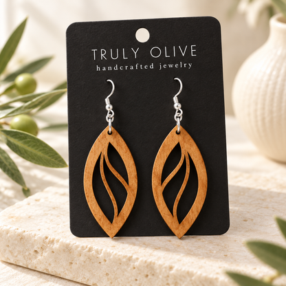 Open Leaf wood earrings in Cherry stain on a black Truly Olive card in a softly lit styled setting.