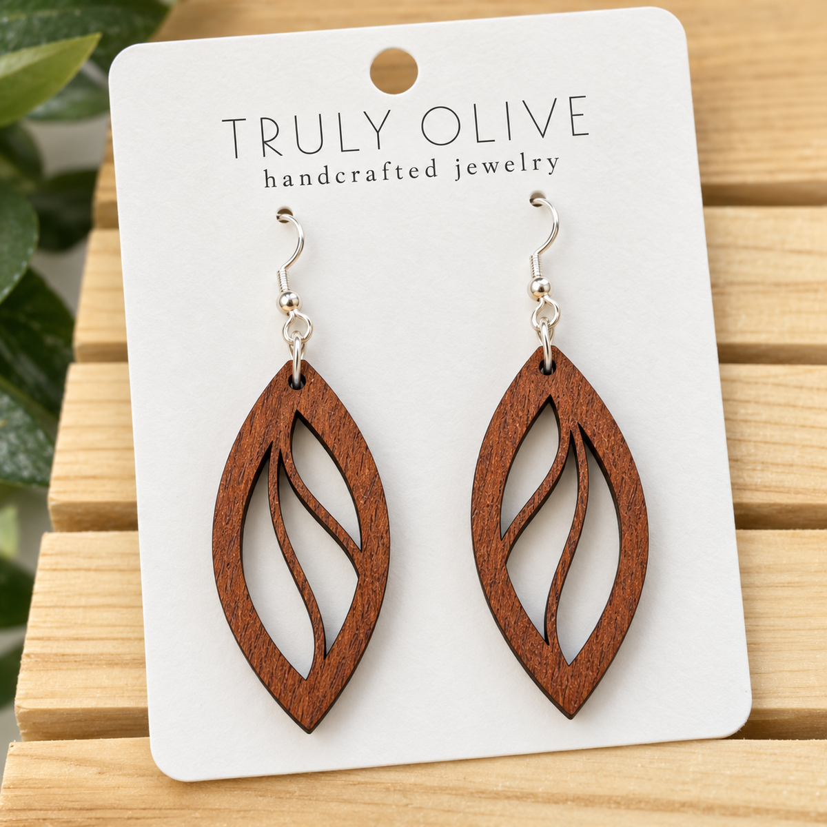 Close view of Sapele Open Leaf wood earrings showing the wood grain and cutout pattern on a white Truly Olive card.
