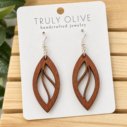 Close view of Sapele Open Leaf wood earrings showing the wood grain and cutout pattern on a white Truly Olive card.
