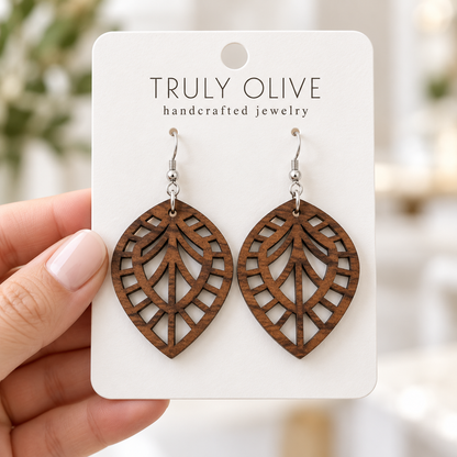 Hand holding a white Truly Olive card with Walnut Leaf Lattice wood earrings.