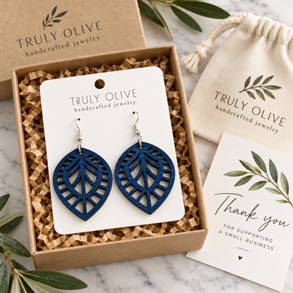 Marine Blue Leaf Lattice wood earrings on a white Truly Olive card in a kraft box beside a branded pouch and thank-you note.