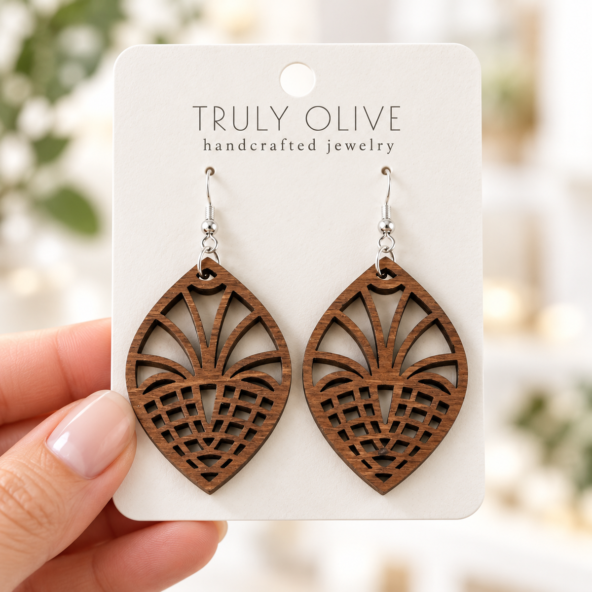 Hand holding a white Truly Olive card with Walnut Fan Lattice wood earrings.