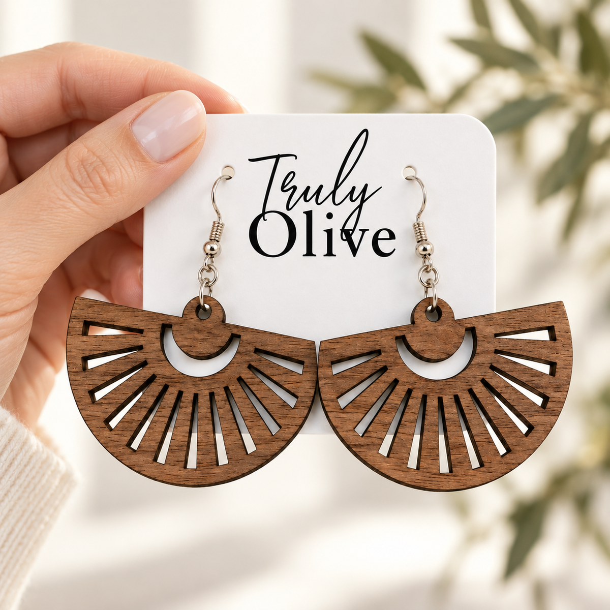 Hand holding Walnut wooden fan earrings on a white Truly Olive card.