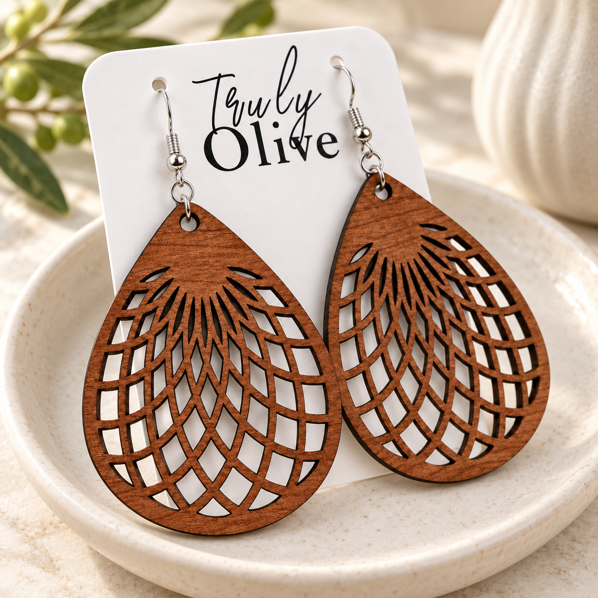 Close-up of Sapele teardrop earrings showing wood grain, lattice cutouts, and silver hooks.