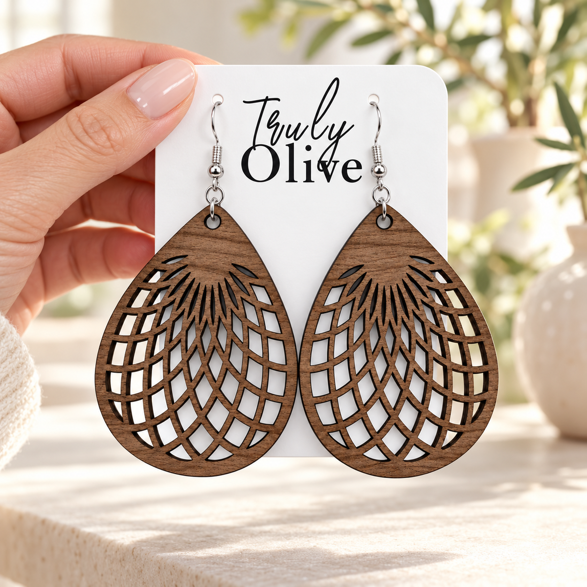 Hand holding Walnut teardrop earrings on a white Truly Olive card.