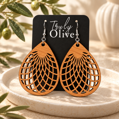 Cherry teardrop earrings on a black Truly Olive card, styled with ivory ceramics and olive greenery.